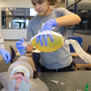 A student practices the use of a manual respirator.